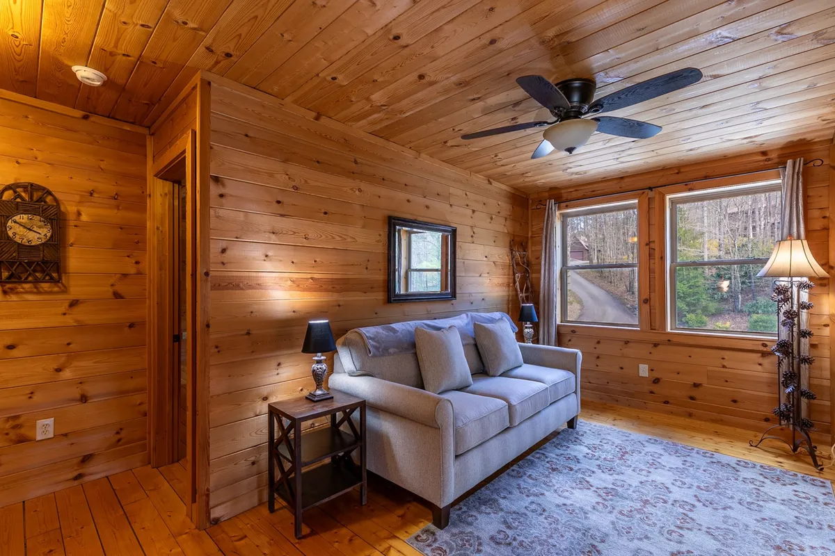 A warmly lit sitting area featuring a sofa, windows, and rustic wood paneling. The space is inviting, perfect for relaxing after a day spent outdoors. Windows provide natural light and glimpses of the surrounding landscape.
